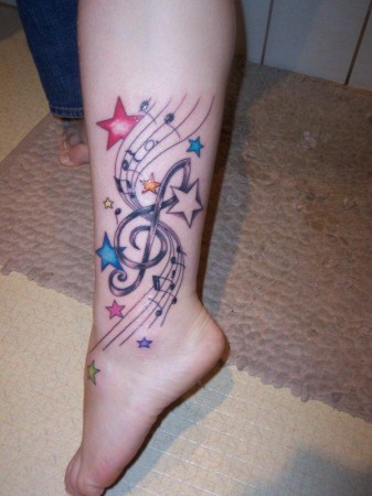 notas musicales en tatuaje a color en pierna
